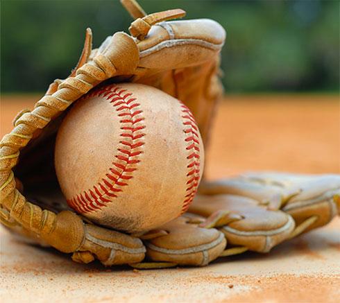 baseball glove on ground holding baseball